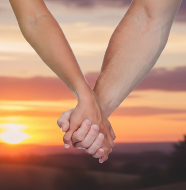 Mani intrecciate al tramonto, simbolo di connessione e amore sotto un cielo mistico